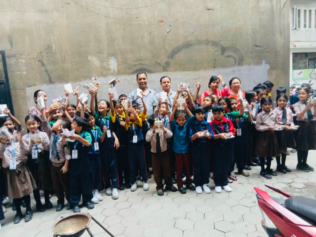 A group of children and adults gathered together with supplies in a school courtyard