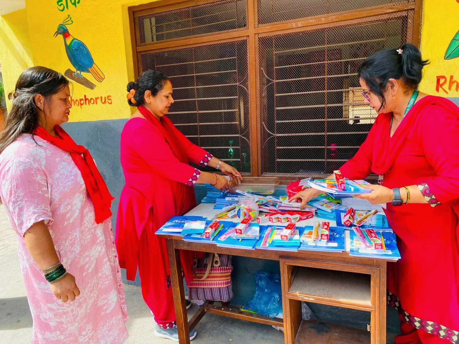 Three adults standing beside a table of colorful school supplies