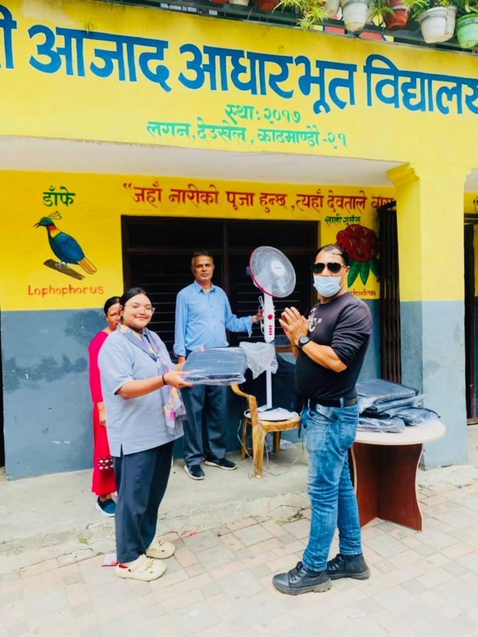 Three people standing outside a school with a classroom fan